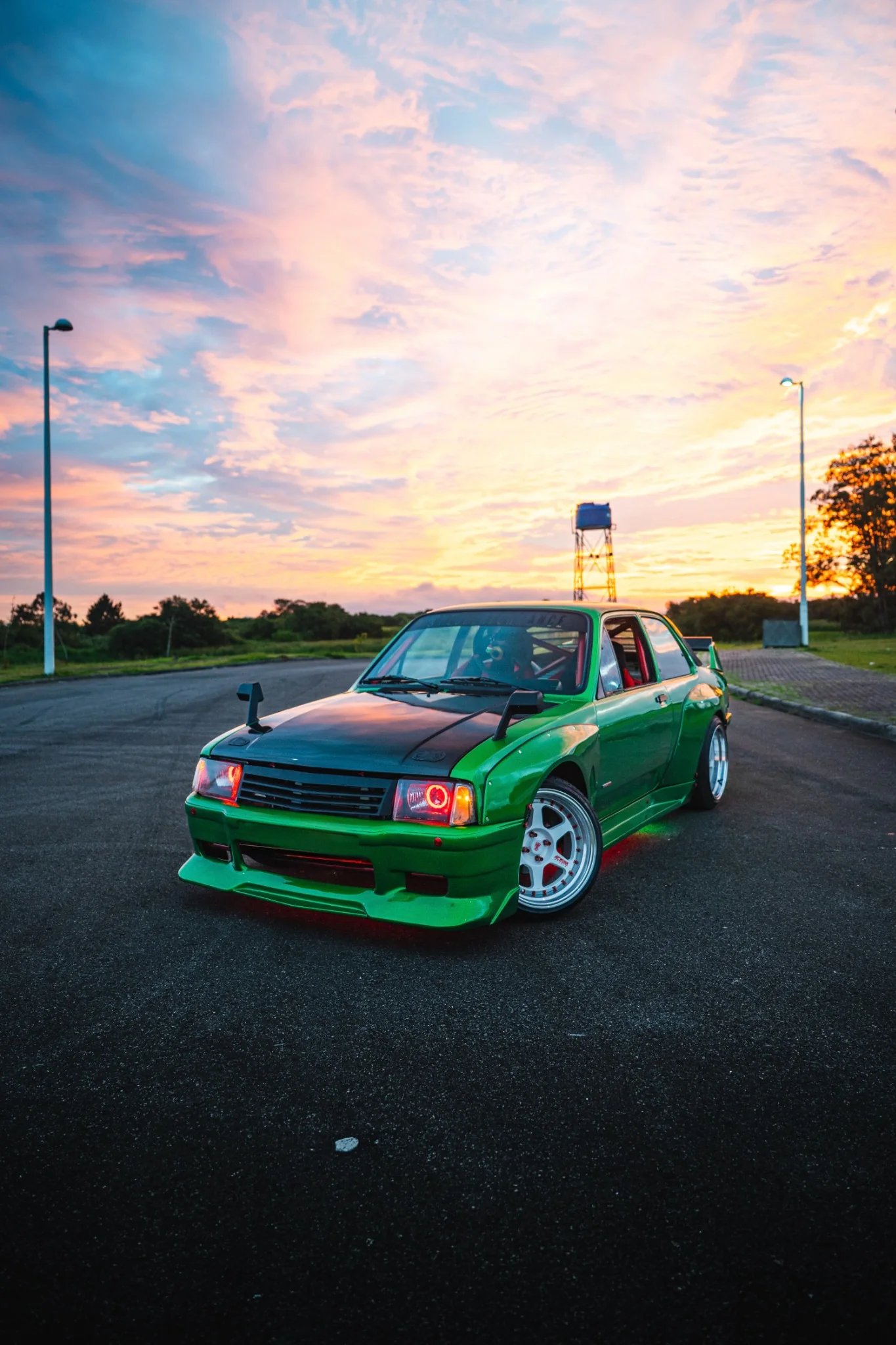 Chevette Grinch ao pôr do sol, com os faróis e a iluminação vermelha acesos