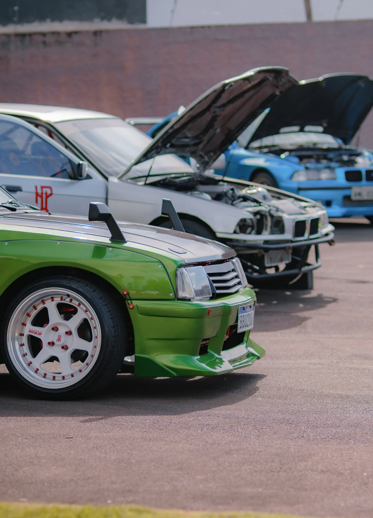 Chevette Grinch ao lado das BMWs da HeuPerformance, com os capôs abertos